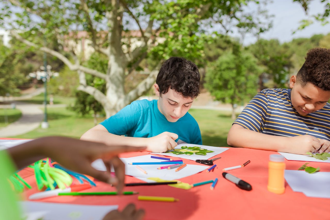 services-03 Children enjoy arts and crafts under trees at a summer camp, fostering creativity.